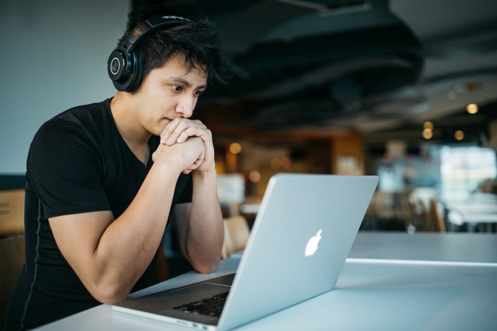 person working wearing a headphone with focus in-front of MacBook