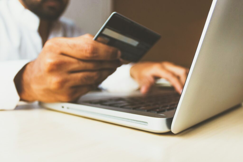 man holding card while using laptop