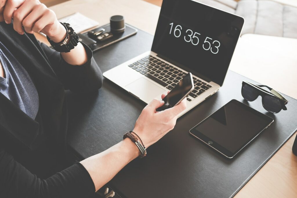 man holding mobile and laptop and ipad in the table